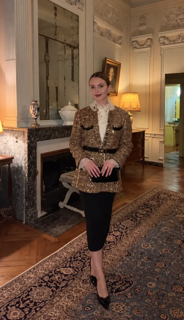 Woman wearing a belted gold sequin blazer over an ivory ruffled blouse, black pencil skirt, and pointed black heels for a glamorous Christmas party outfit.