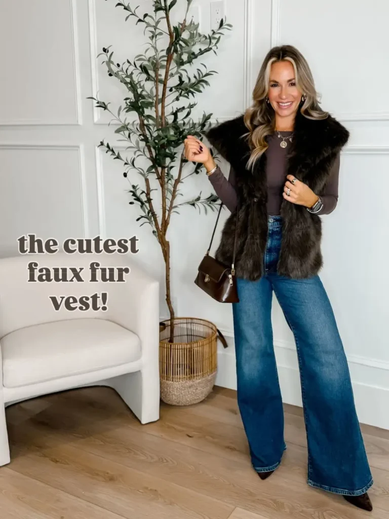 Woman wearing a dark brown faux fur vest over a fitted taupe long-sleeve top with blue wide-leg jeans and a small brown handbag for a stylish Thanksgiving outfit.
