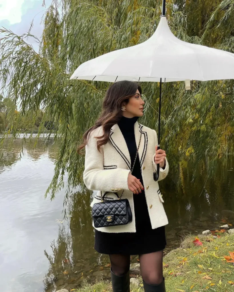 Cream contrast-trim blazer with black turtleneck, black mini skirt, sheer tights, and knee-high boots.