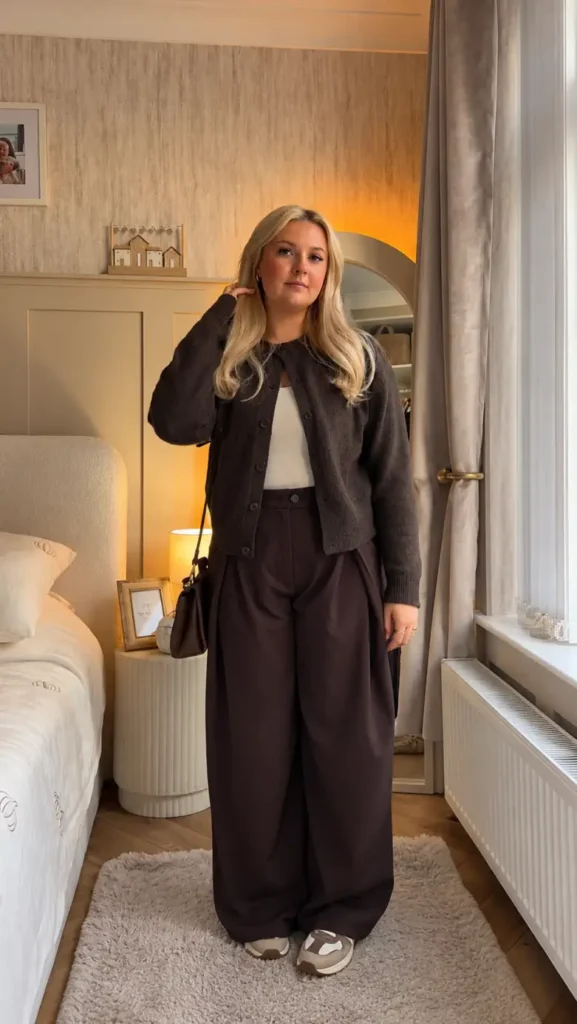 Petite woman wearing a dark brown cardigan over a white top with chocolate wide-leg trousers and casual sneakers for a cozy fall look.