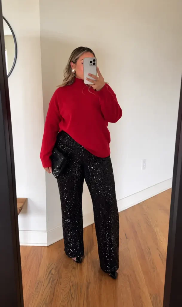 Woman wearing a bright red turtleneck sweater with black sequin wide leg trousers, a matching sparkly clutch, and pointed heels for a cozy chic Christmas outfit.