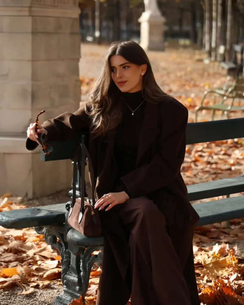 Chocolate brown oversized blazer and wide-leg trousers styled with a dark turtleneck and brown handbag for sophisticated autumn fashion.