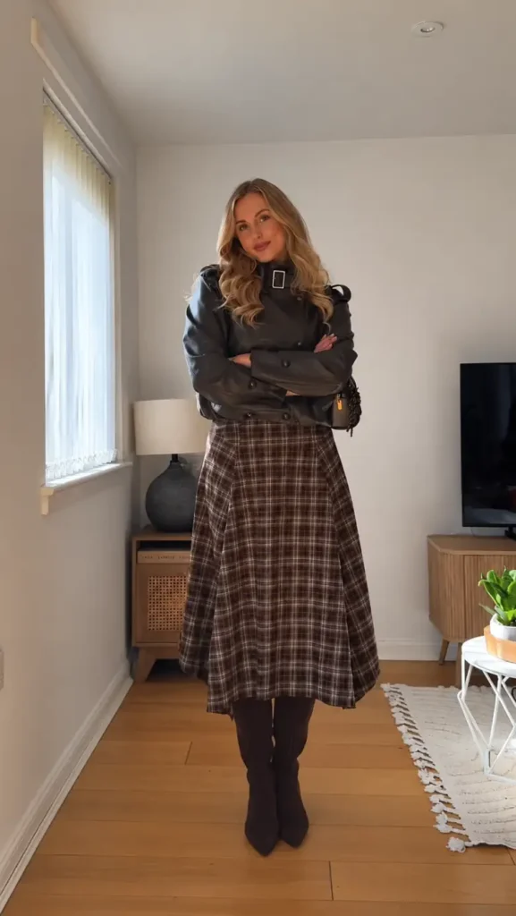 Dark leather jacket paired with a brown plaid midi skirt and tall brown boots for a classic autumn outfit.