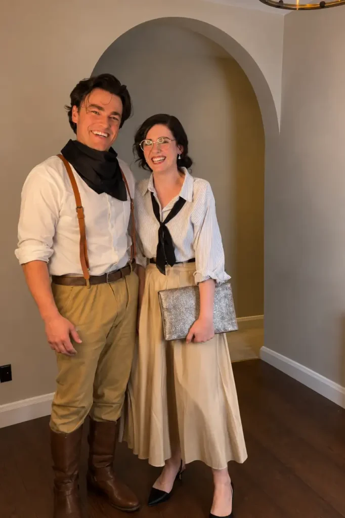 Vintage-inspired couple costume with an explorer outfit and bookish look featuring glasses and a long skirt.
