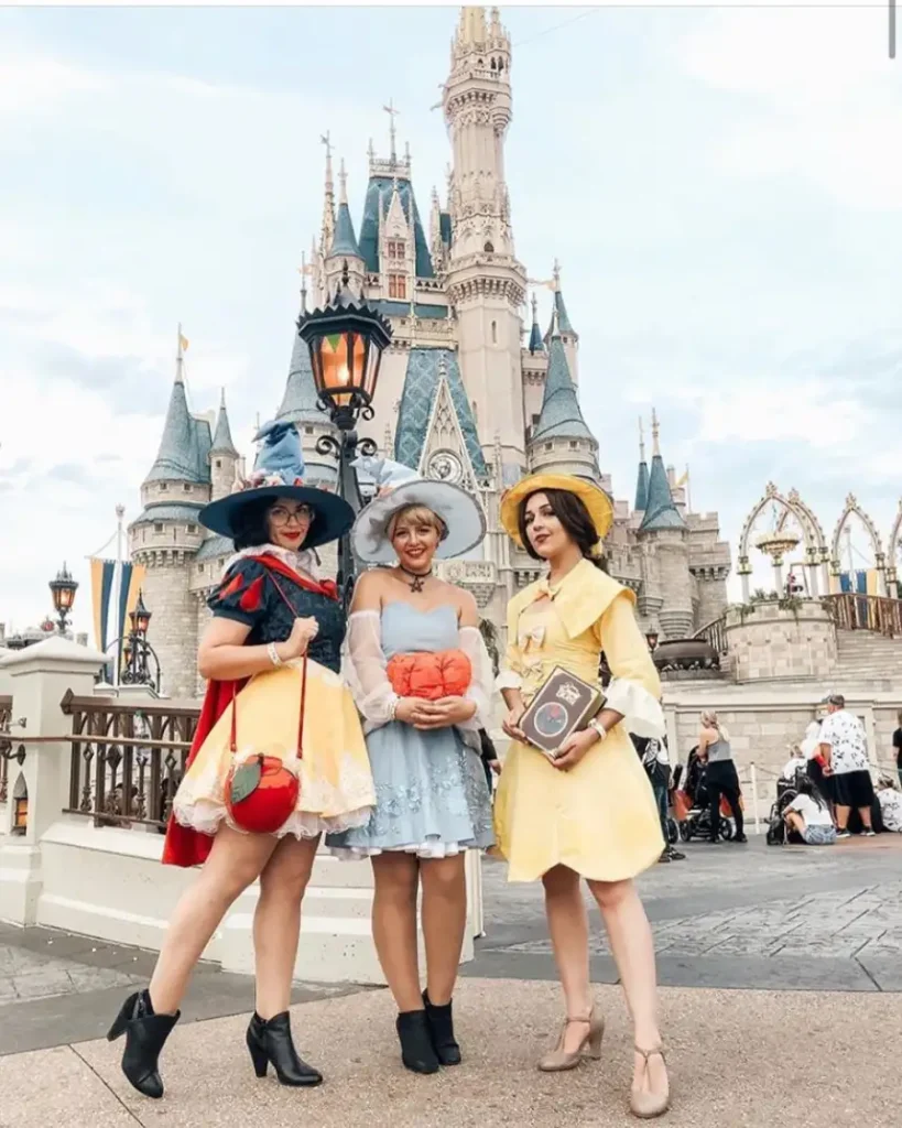 Three women wearing coordinated red, powder blue, and yellow fairytale witch costumes with oversized hats and themed accessories.