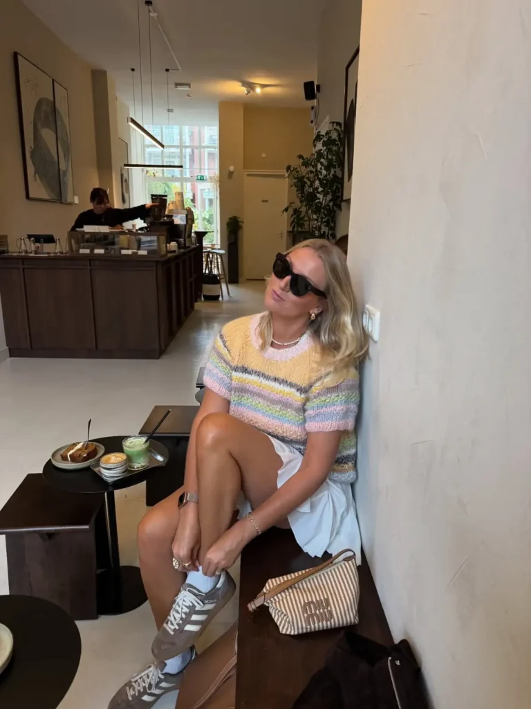 Pastel striped knit top with white mini skirt, white socks, neutral sneakers, and striped handbag.