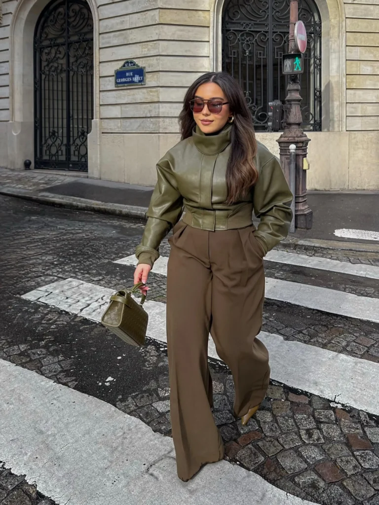 Cropped olive leather jacket paired with brown wide-leg trousers, an olive handbag, and sunglasses for an earthy fall outfit.