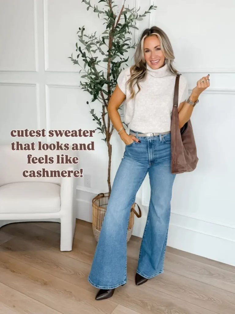 Woman wearing a cream short-sleeve turtleneck sweater with blue flared jeans, a light-colored belt, dark pointed-toe boots, and a brown shoulder bag for a chic Thanksgiving outfit.