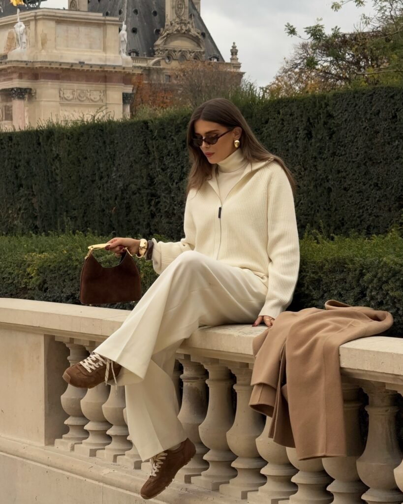 Cream turtleneck and ribbed zip cardigan styled with ivory wide-leg trousers, brown sneakers, and a brown handbag for neutral fall fashion.