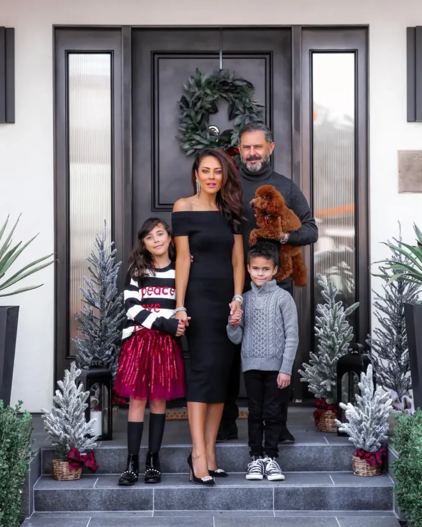 Family wearing black and gray outfits with Mom in a black off-shoulder dress, Dad in a charcoal turtleneck, daughter in a red sequin skirt, and son in a gray cable-knit sweater.