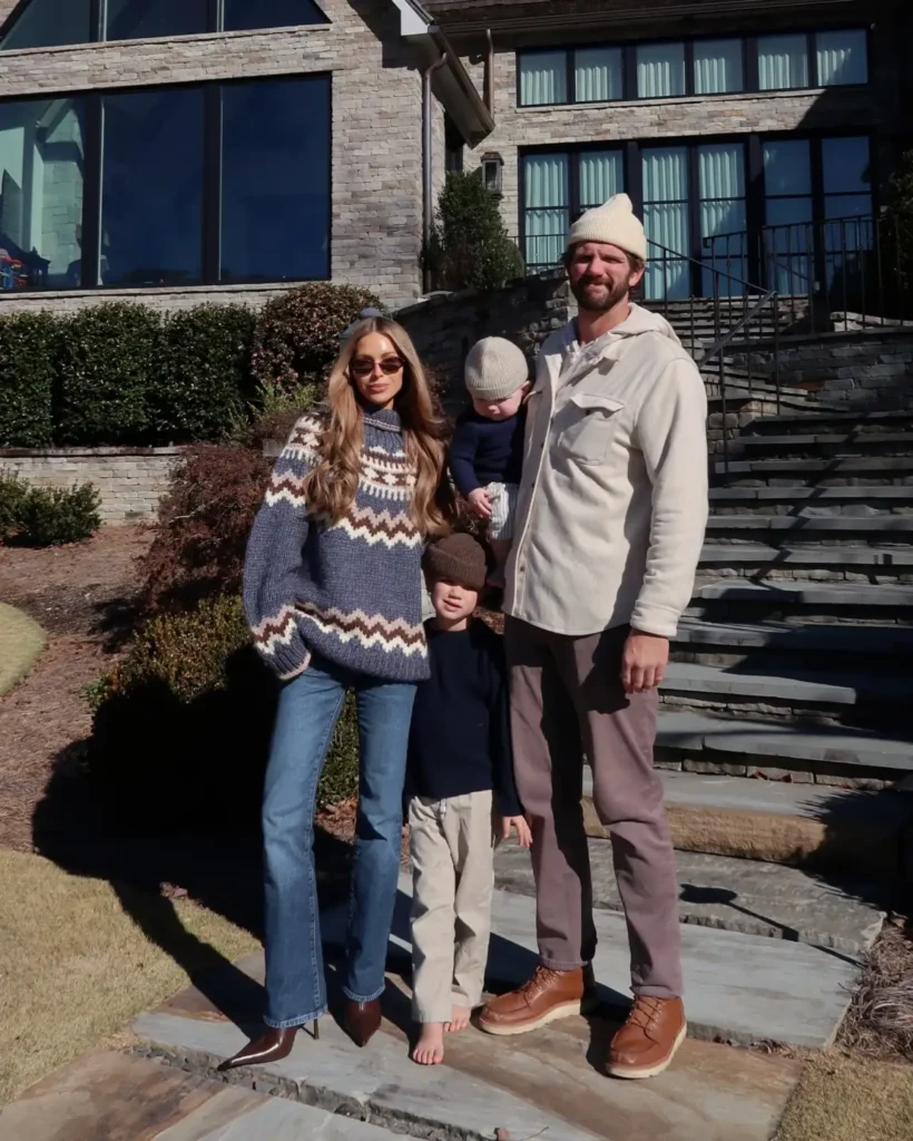 Family wearing cozy fall outfits with Mom in a blue Fair Isle sweater and jeans, Dad in a cream fleece overshirt, and two children in navy knits, light trousers, and beanies.