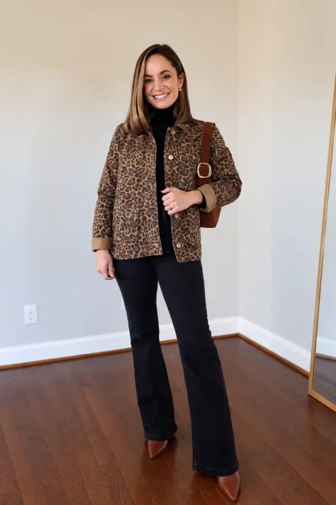 Woman styling a leopard print jacket over a black turtleneck with black flared jeans, brown pointed-toe boots, and a brown shoulder bag for a chic fall dinner outfit.