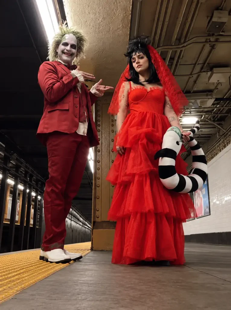 Spooky couple Halloween costumes featuring a red-suited ghost groom and a bride in a dramatic layered red dress and veil.