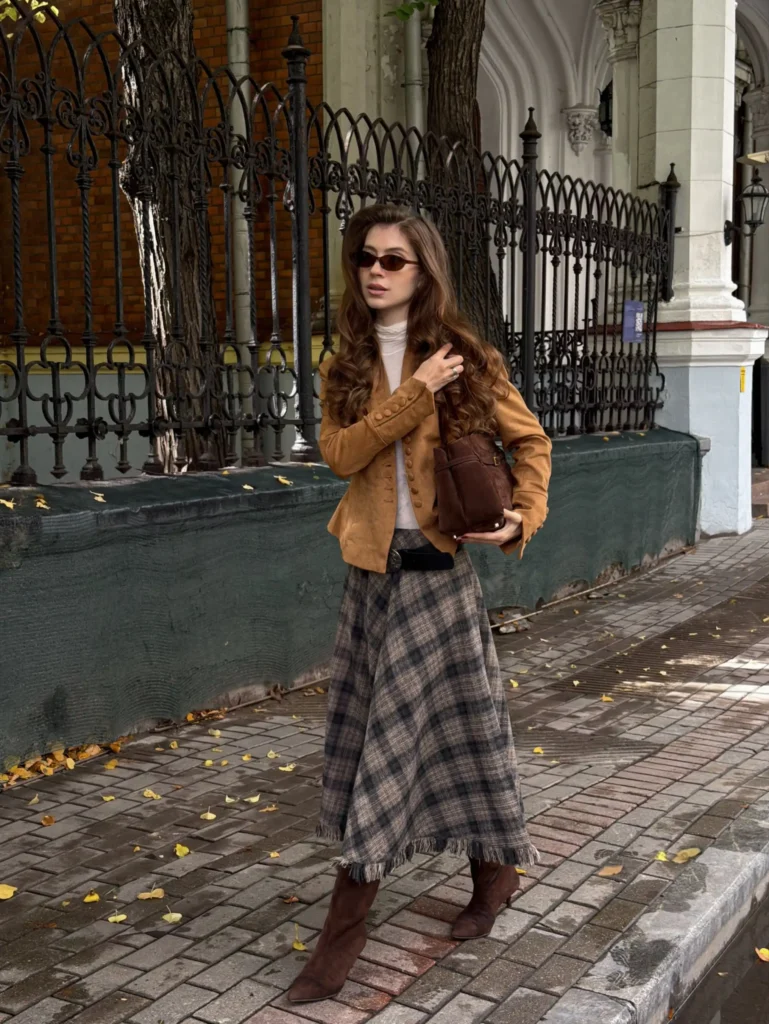 Camel jacket styled with a long brown plaid midi skirt, brown knee-high boots, a cream top, and a dark brown shoulder bag for fall.