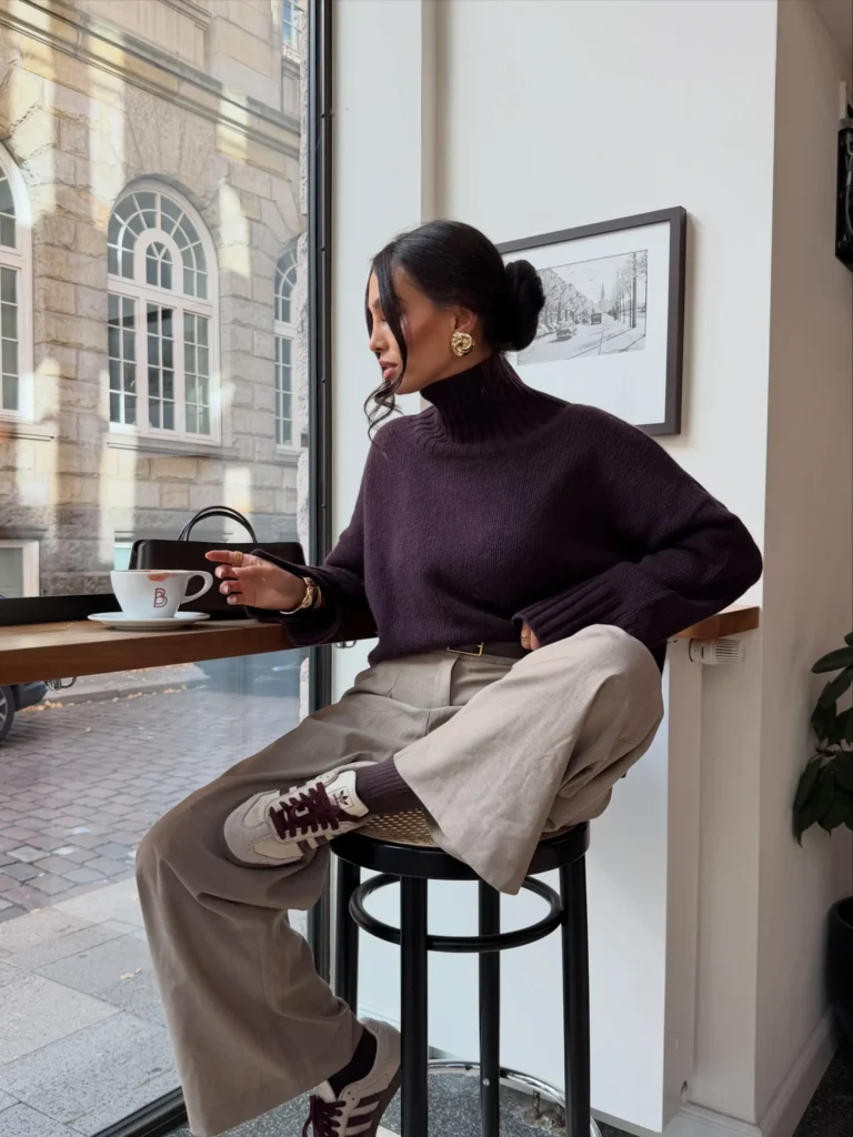 Burgundy turtleneck sweater styled with taupe wide-leg trousers and retro sneakers for a polished casual fall outfit for women.