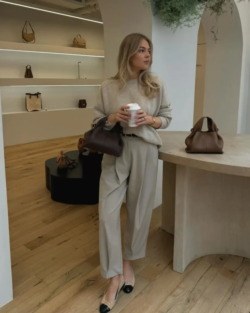 Oatmeal sweater tucked into light beige tailored trousers with two-tone ballet flats for a simple neutral fall outfit for women.
