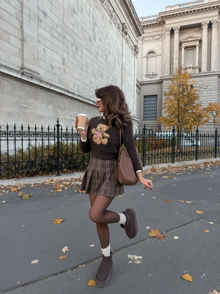 Woman wearing a dark chocolate-brown teddy sweater, brown plaid pleated mini skirt, sheer brown tights and chocolate platform shoes for a preppy fall outfit.