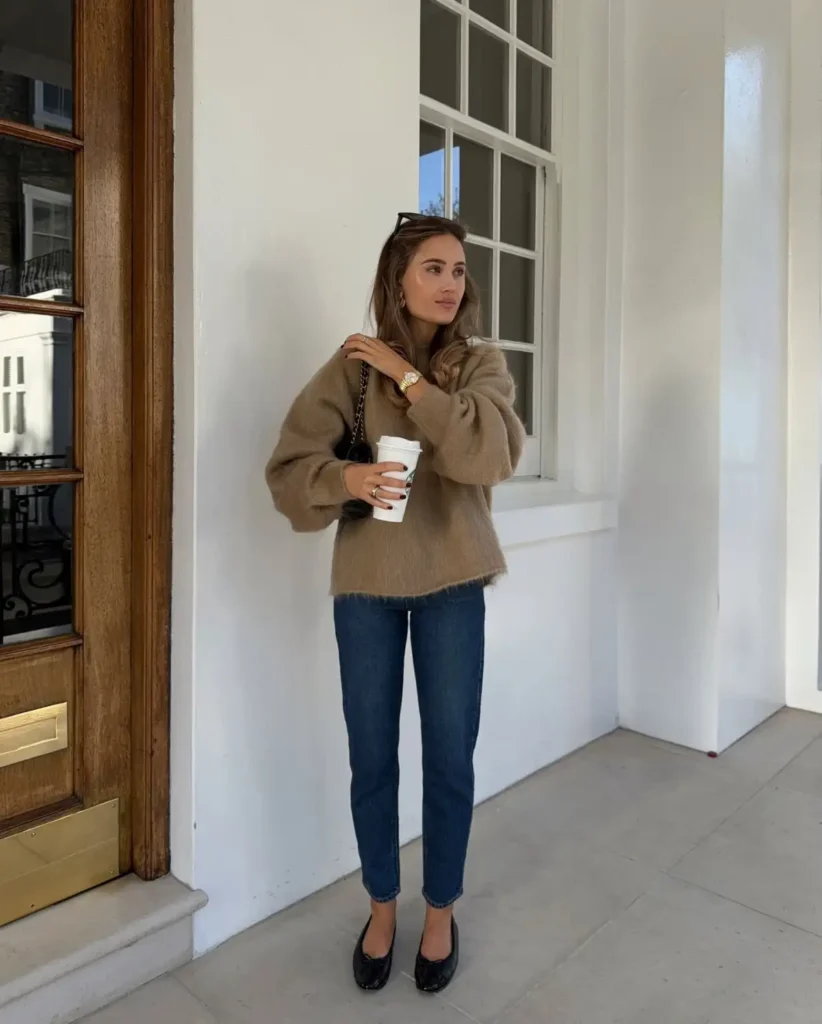 Woman wearing a fuzzy camel-brown sweater with dark indigo-blue straight-leg jeans and black ballet flats for a casual everyday fall outfit.