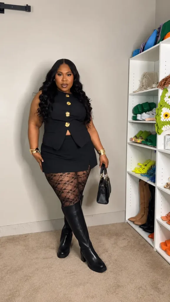 Plus size Black woman wearing a fitted black vest, short skirt, sheer lace tights, and tall black boots for a stylish fall evening outfit.