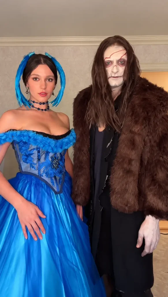 Spooky couple Halloween costumes featuring a bright blue ballgown paired with a dark fur-covered scarred monster look.