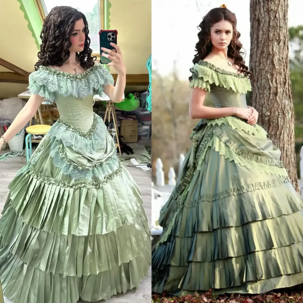 Woman wearing a sage green Victorian-style gown with lace neckline, fitted corset bodice, layered ruffled skirt, and dark curled hair.