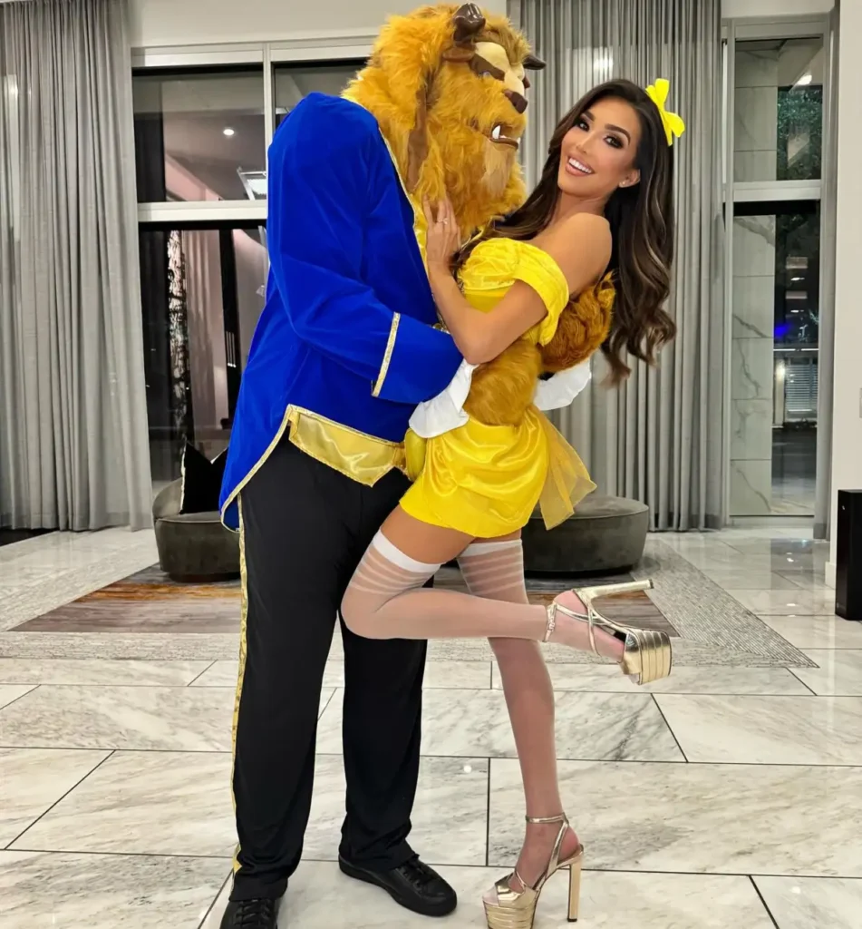 Couple wearing Beauty and the Beast costumes with Belle in yellow and Beast in a blue jacket.