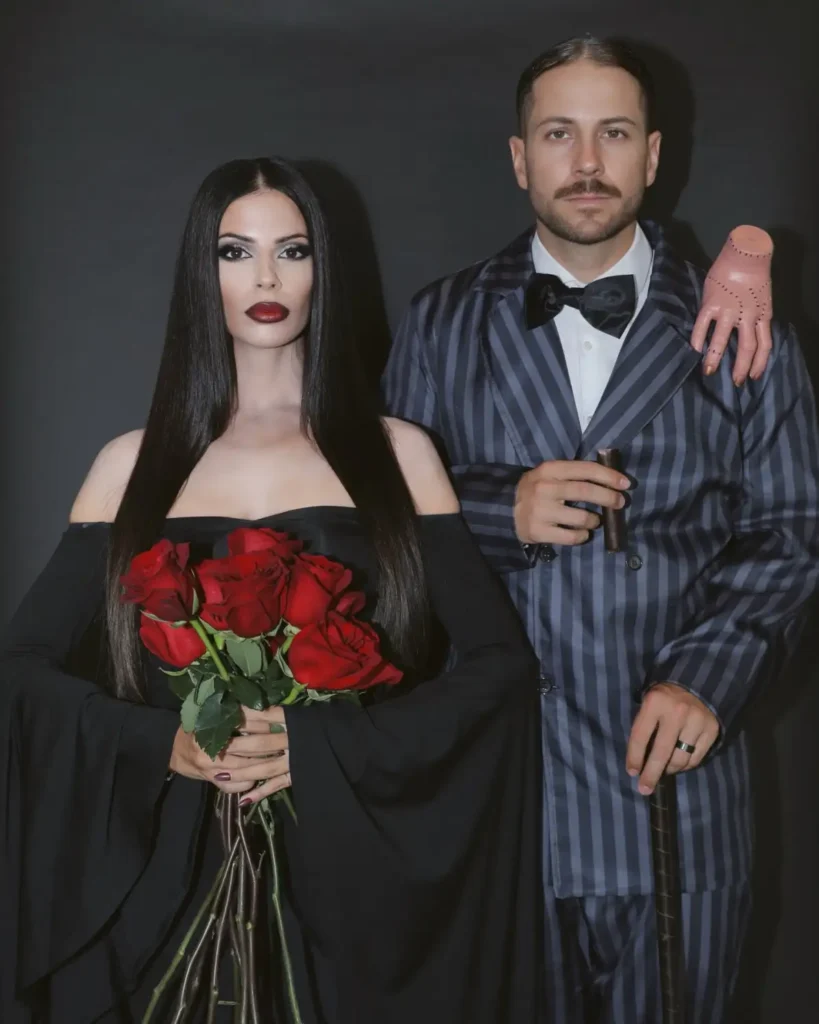 Morticia and Gomez couple Halloween costume with black dress, striped suit and red roses