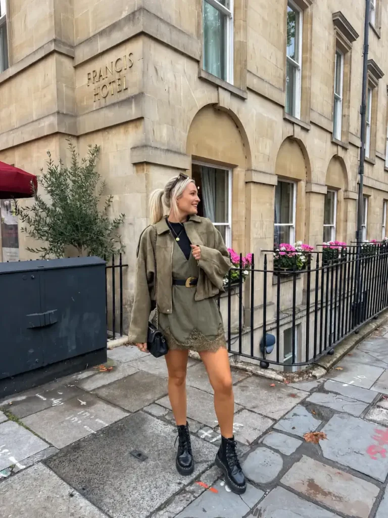 Olive green jacket and matching mini skirt styled with a black top, belt, crossbody bag, and black combat boots for a casual fall outfit.