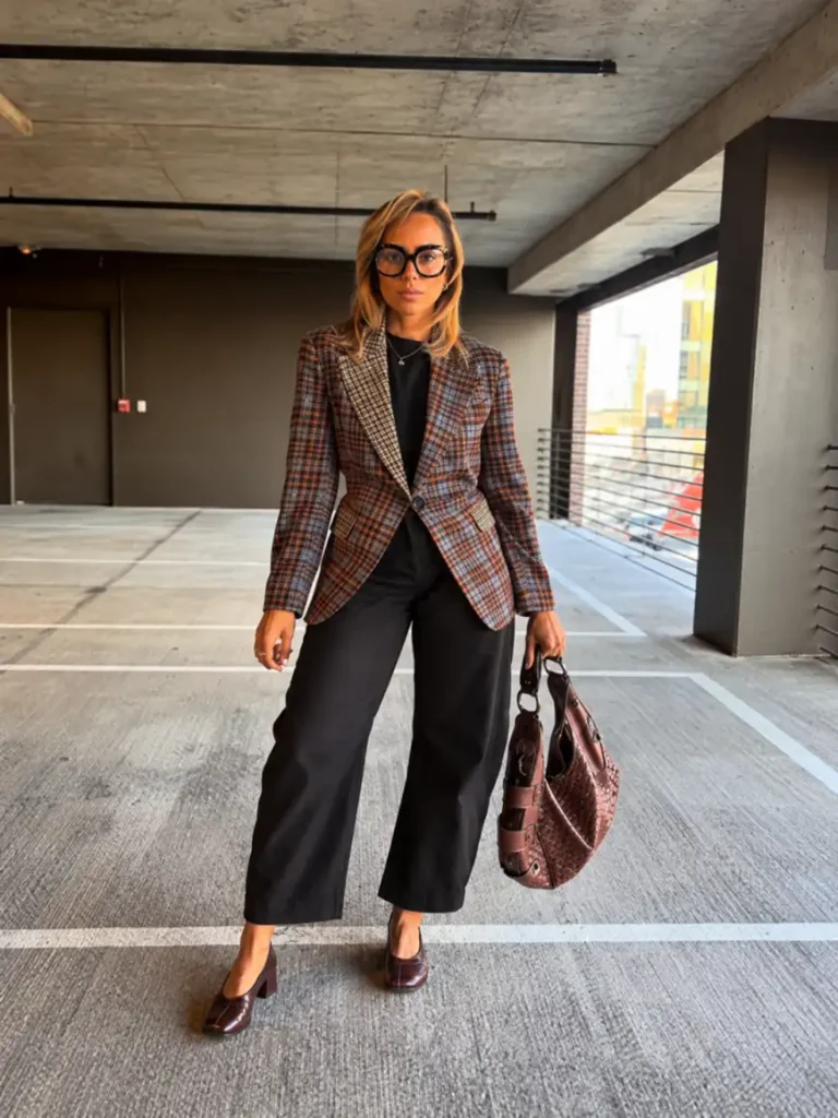Woman wearing a brown checked blazer with a black top, cropped wide-leg trousers, burgundy Mary Jane heels, and a woven handbag for sophisticated fall office fashion.