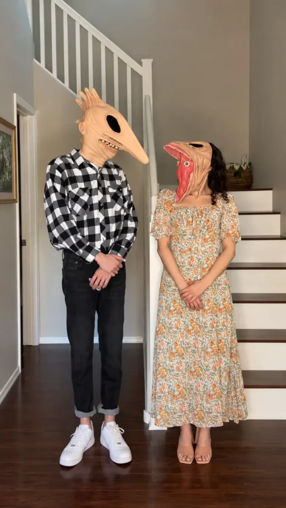 Couple wearing creepy oversized monster head masks with simple everyday clothing for Halloween.