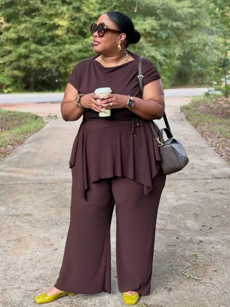 Plus size Black woman wearing a chocolate brown pleated matching set with bright yellow-green flats for a stylish monochrome fall outfit.