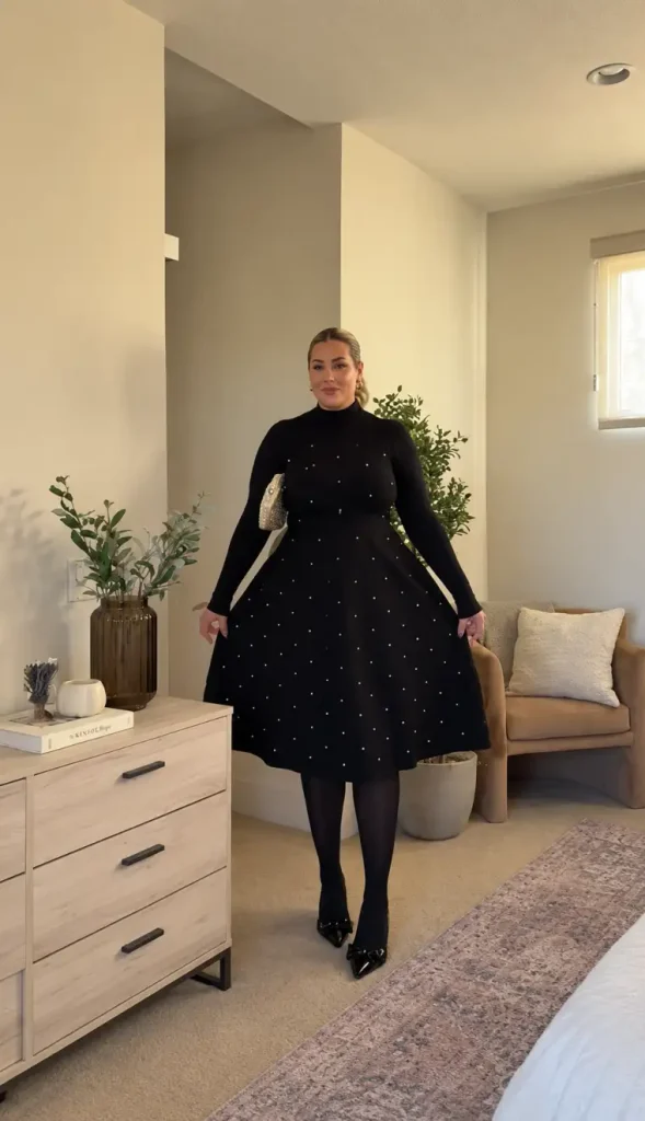 Woman wearing a black turtleneck top with a flared pearl-studded midi skirt, black tights, pointed bow heels, and a sparkling shoulder bag for a classy Christmas look.